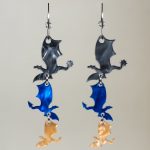 Pendientes pequeños de metacrilato acrílico con forma de dragón de los libros Fourth Wing, Alas de Sangre en colores azul, gris y dorado.